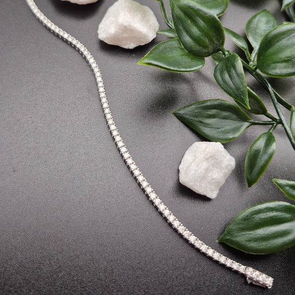 Moissanite tennis bracelet UK styled on black background with florals — Dewdrop Sparkle luxury jewellery gift for her — Lilies of the Valley
